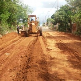 Na foto, uma rua com chão de terra e maquinários da EMDEF trabalhando no local