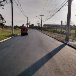Na foto, uma rua recém recapeada pela EMDEF, ao fundo maquinário utilizado no recapeamento